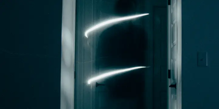 Halb geöffnete Tür in einem dunklen Raum, Lichtspuren auf dem Türblatt